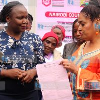 Nairobi Women Rep Esther Passaris hands over a bank slip to FIDA Executive Director Teresa Omondi