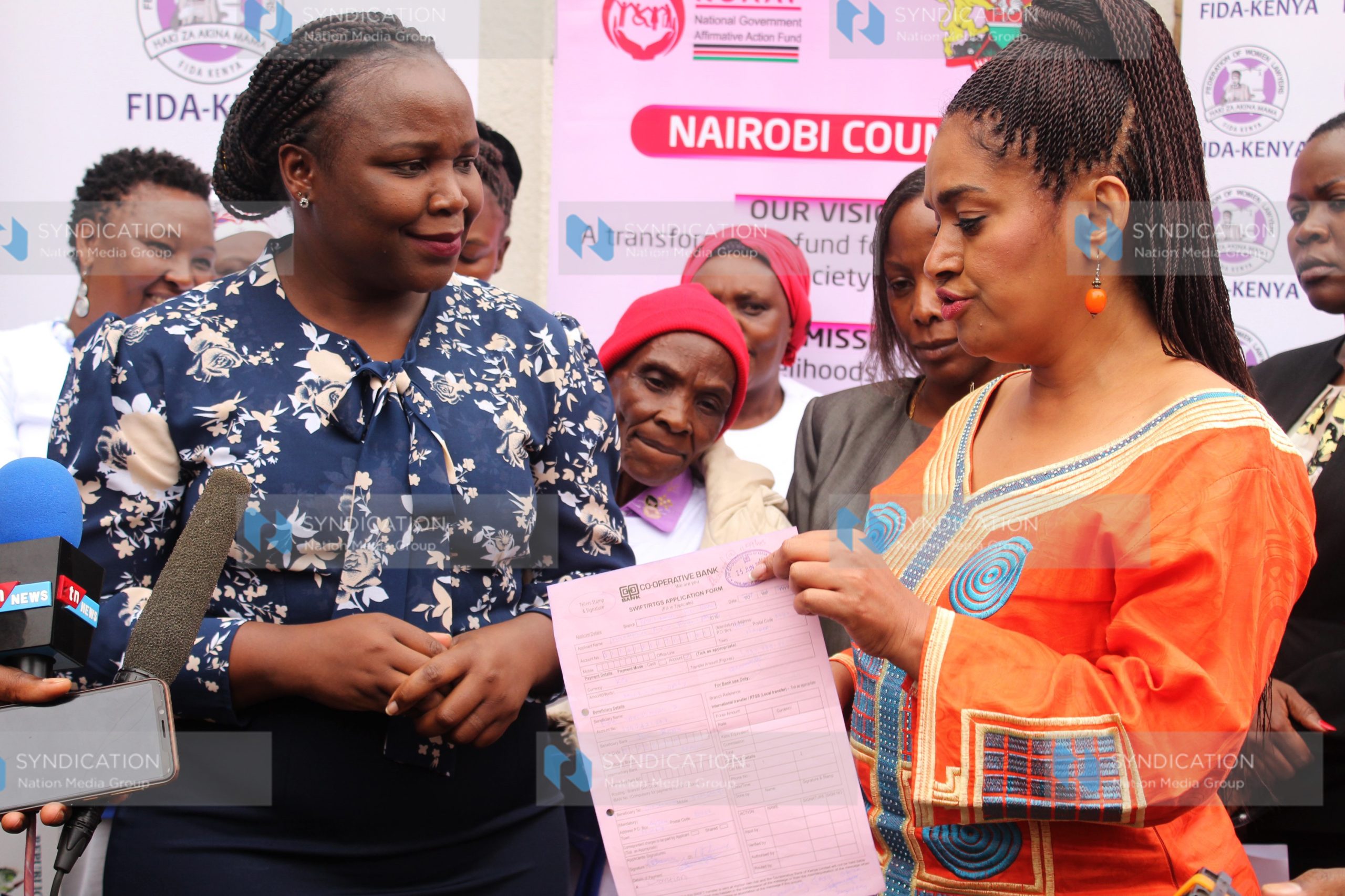 Nairobi Women Rep Esther Passaris hands over a bank slip to FIDA Executive Director Teresa Omondi