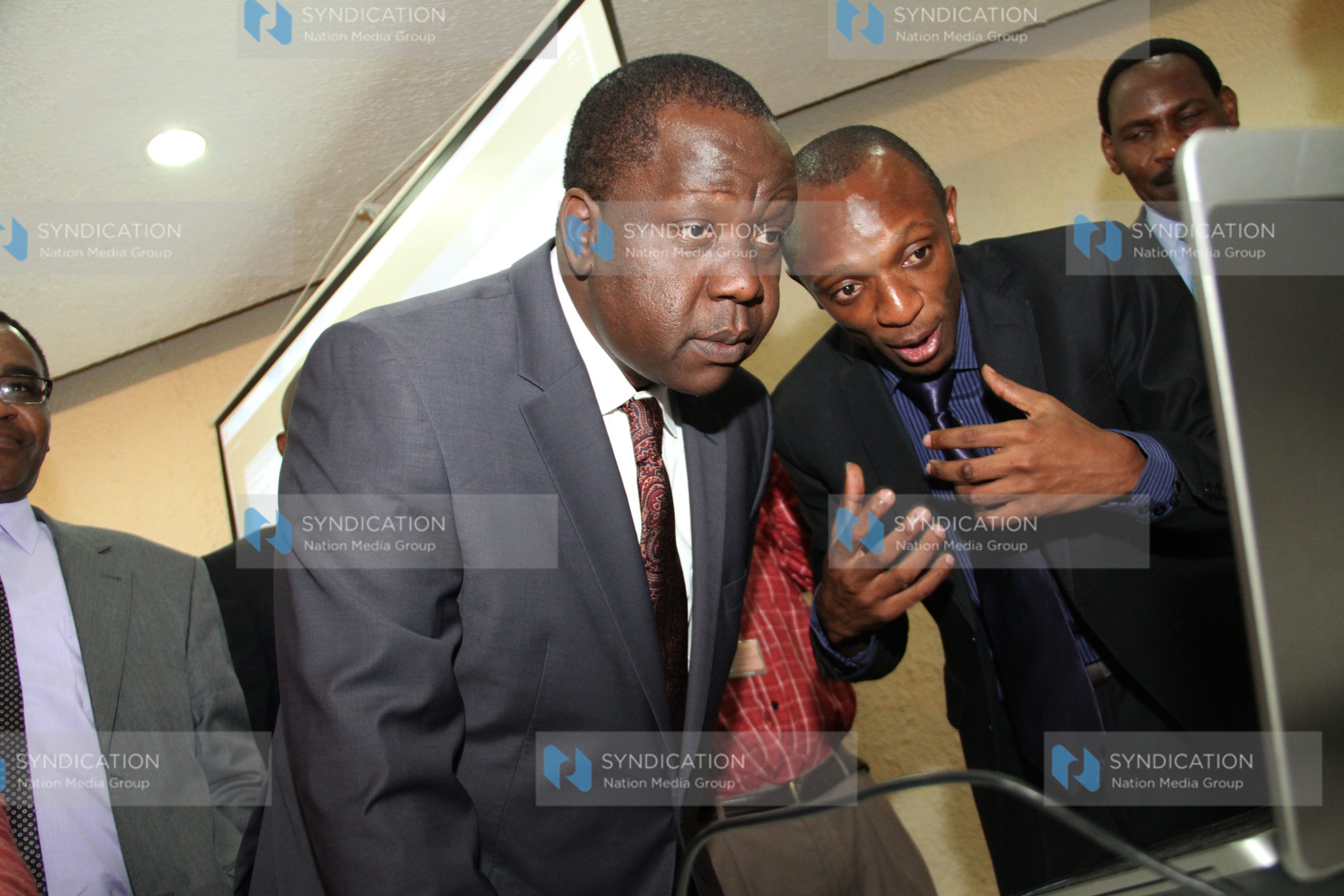 ICT Cabinet Secretary Fred Matiang’i and IRA actuarial officer Elias Omondi