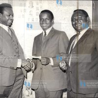 Mwangi Kariuki popularly known as JM in his Nairobi office presenting a cheque for 1,000/=
