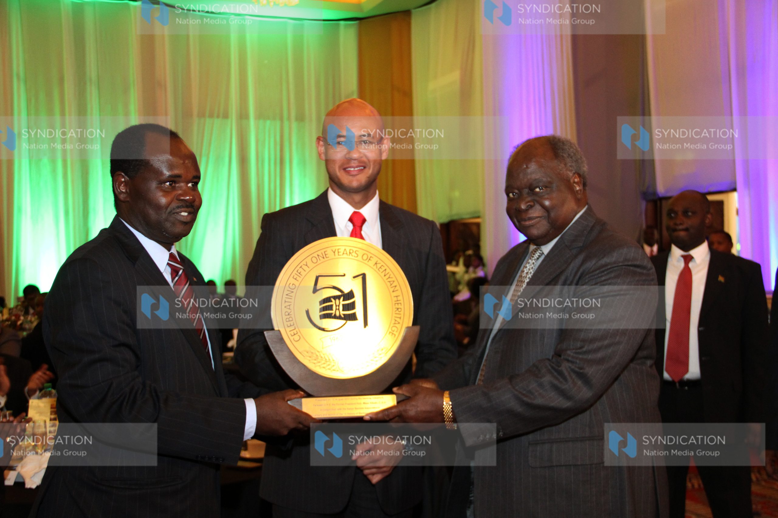 Former President Mwai Kibaki (R) receives a token of appreciation