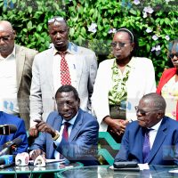 Collins Oyuu (seated center) gestures during a joint media briefing