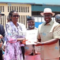 President William Ruto(right) presents a title deed to a resident of Kibiru in Tigania West