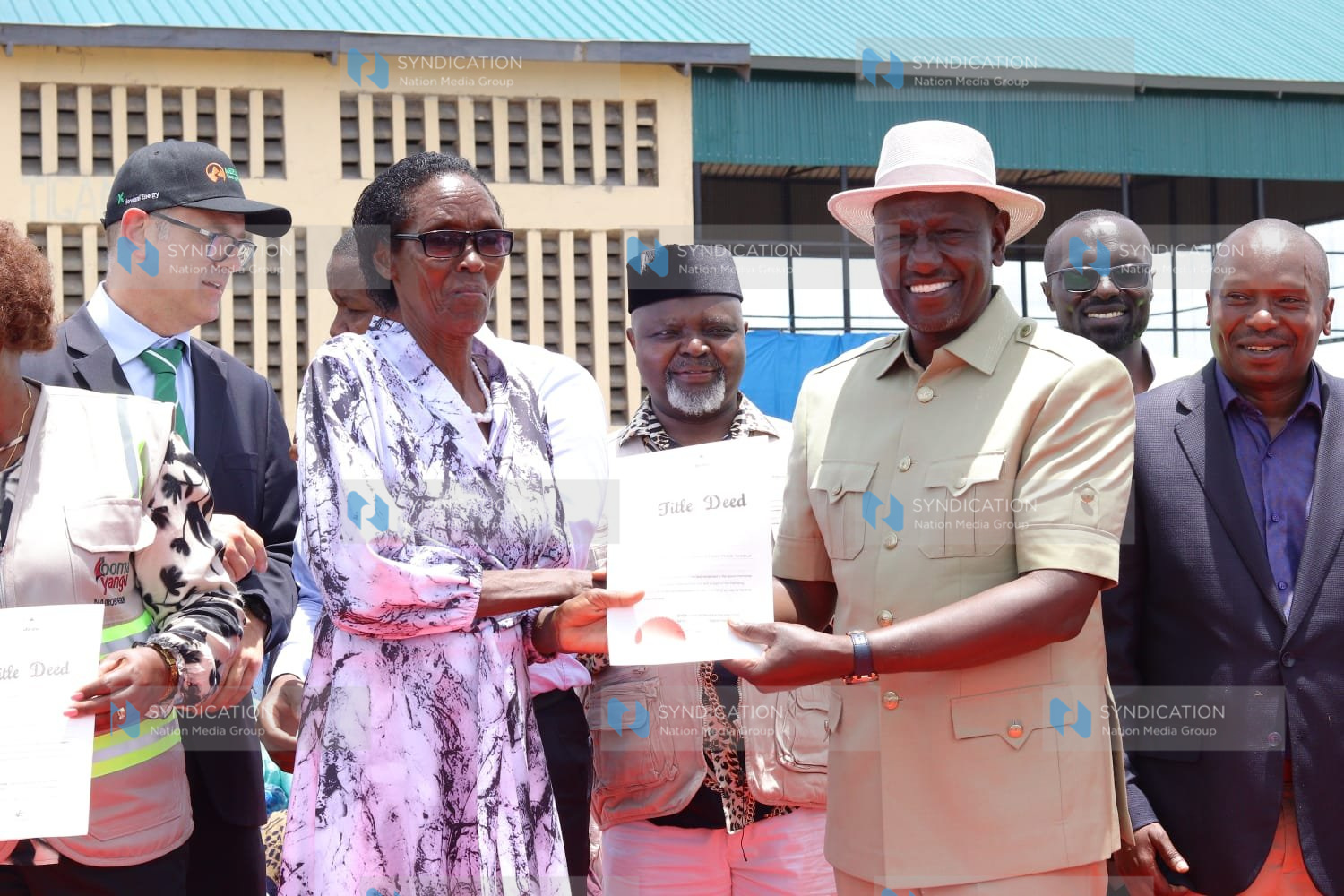 President William Ruto(right) presents a title deed to a resident of Kibiru in Tigania West