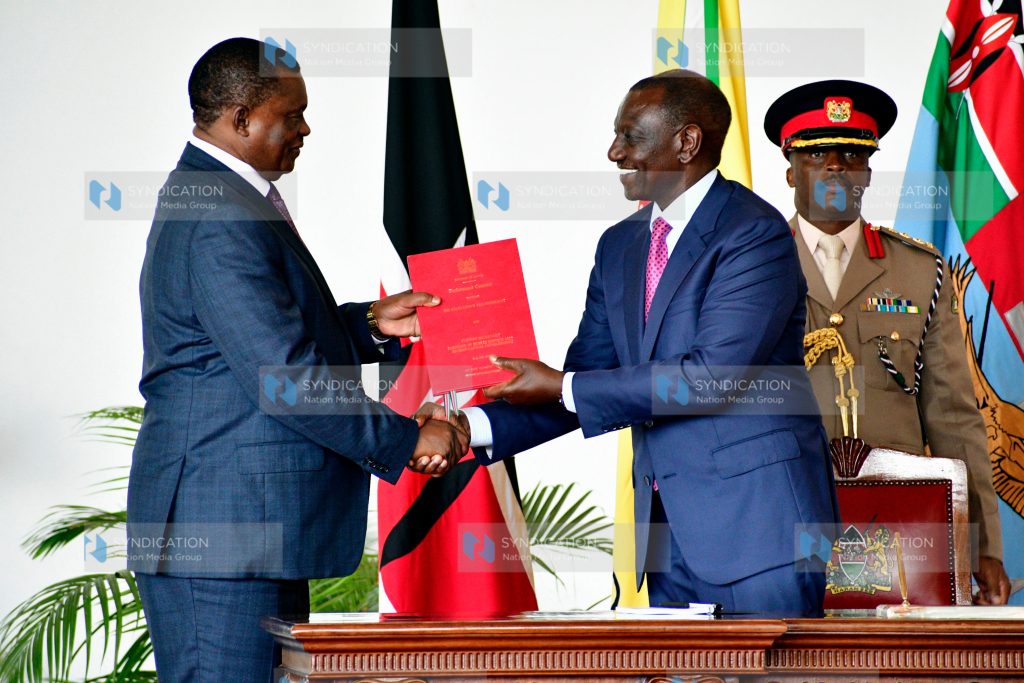 President William Ruto (right) hands over signed documents