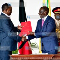 President William Ruto (right) hands over signed documents