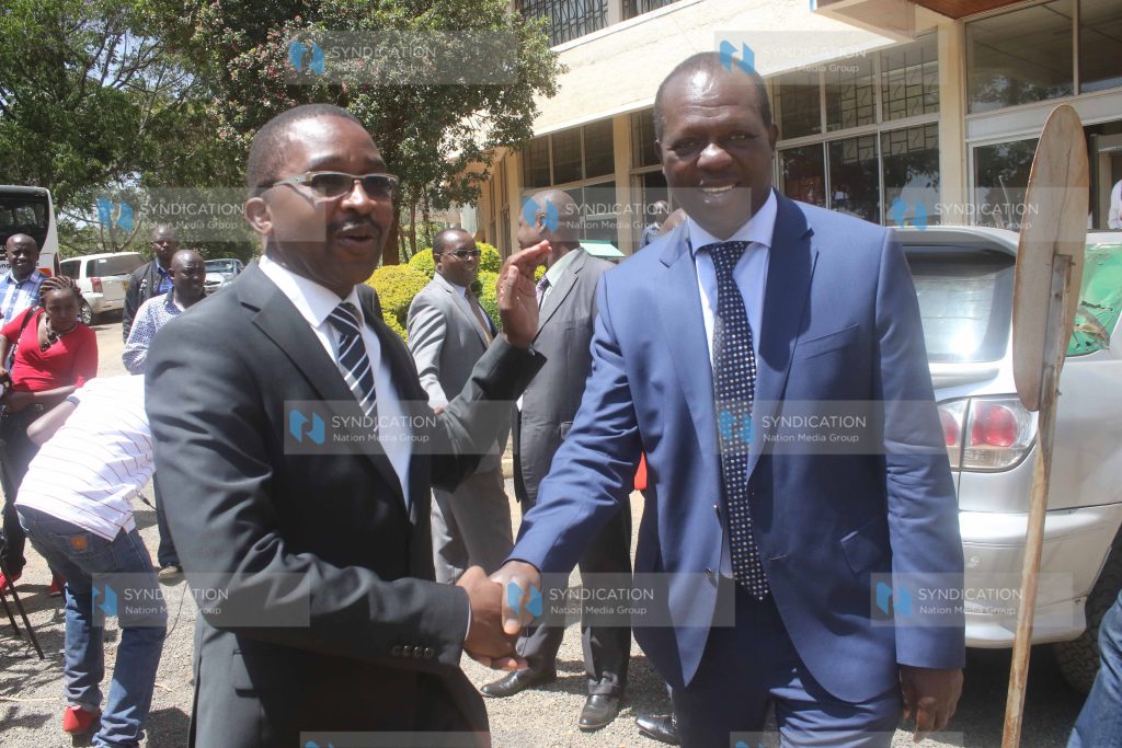 Mwangi wa Iria and Jubilee Party secretary general Raphael Tuju shake hands after addressing journalists