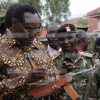 Internal security minister Prof George Saitoti holds a home-made gun as operation rudisha amani tactical advisor Joseph Gituku explains