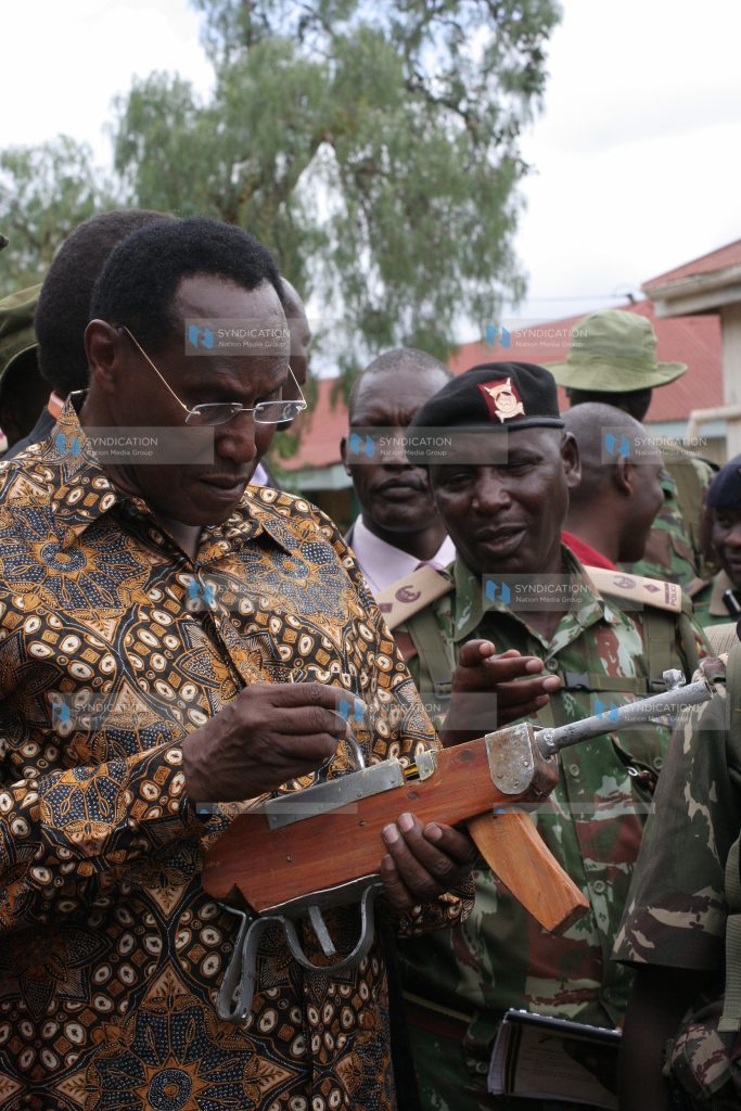 Internal security minister Prof George Saitoti holds a home-made gun as operation rudisha amani tactical advisor Joseph Gituku explains