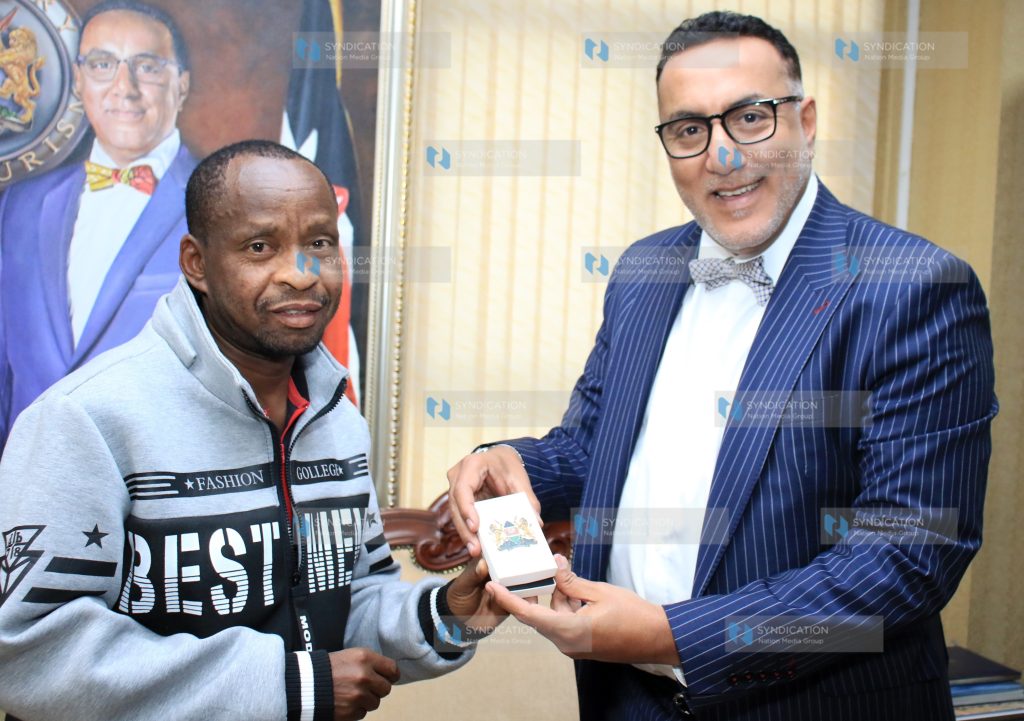 Tourism and Wildlife Cabinet Secretary Najib Balala [R] awards Patrick Kilonzo Mwalua