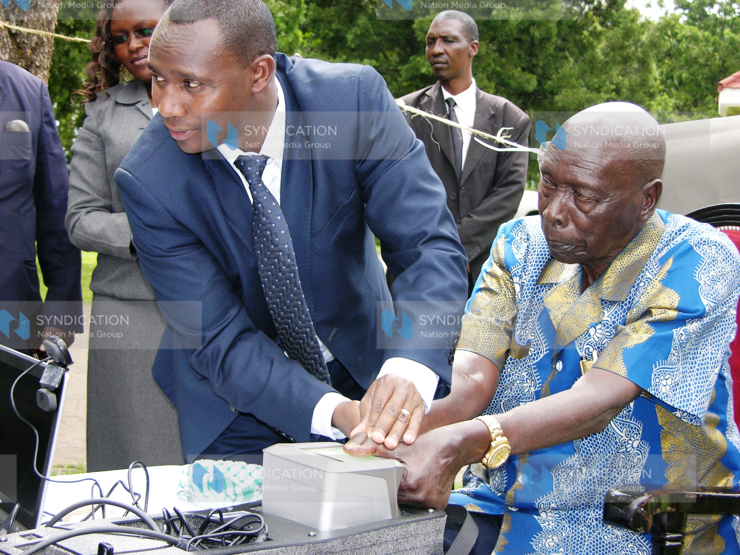 Former President Daniel arap Moi (R) being taken through voter registration exercise
