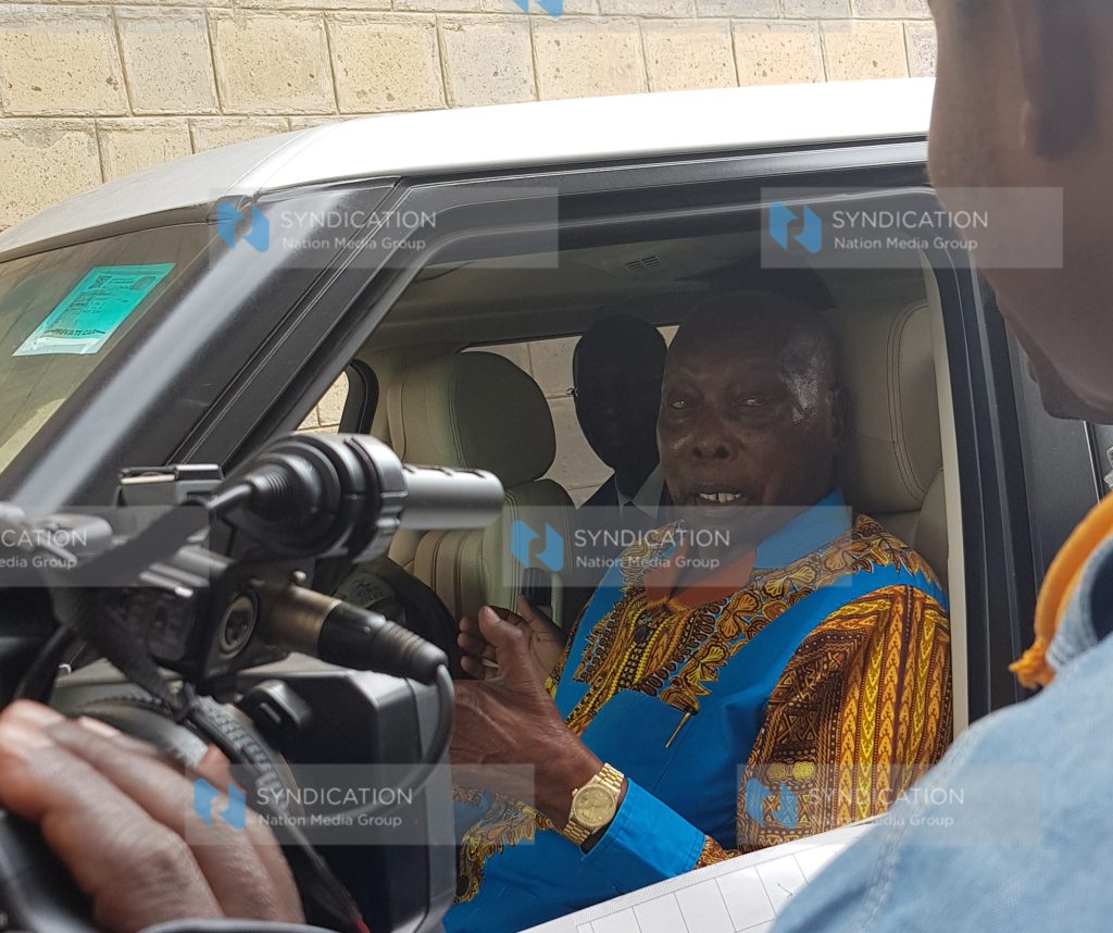 Retired President Daniel Arap Moi chats with a polling clerk after voting