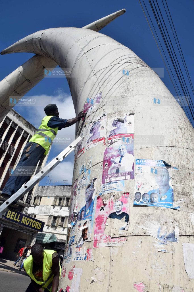 Workers hired by Mombasa Cement remove campaign posters