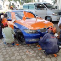 Workers proceed with branding a saloon car with ODM Party colours