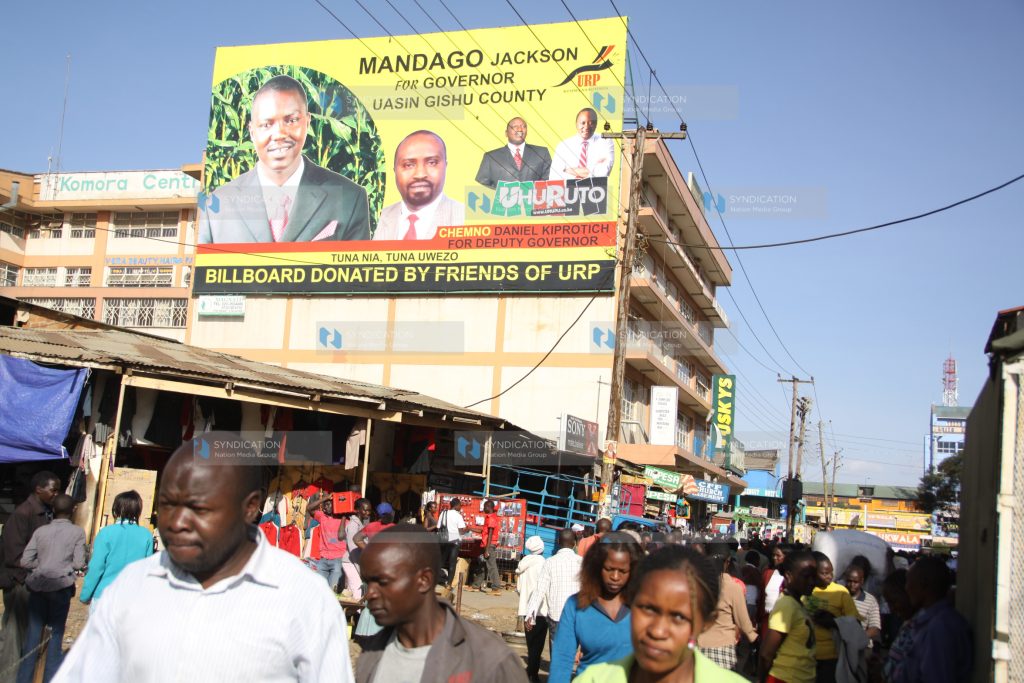 Members of the public walk past a massive campaign billboard