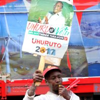 A Jubilee backer lifts placards during a campaign rally