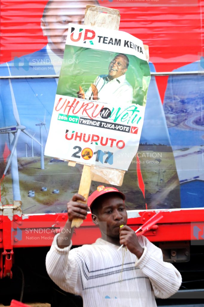 A Jubilee backer lifts placards during a campaign rally