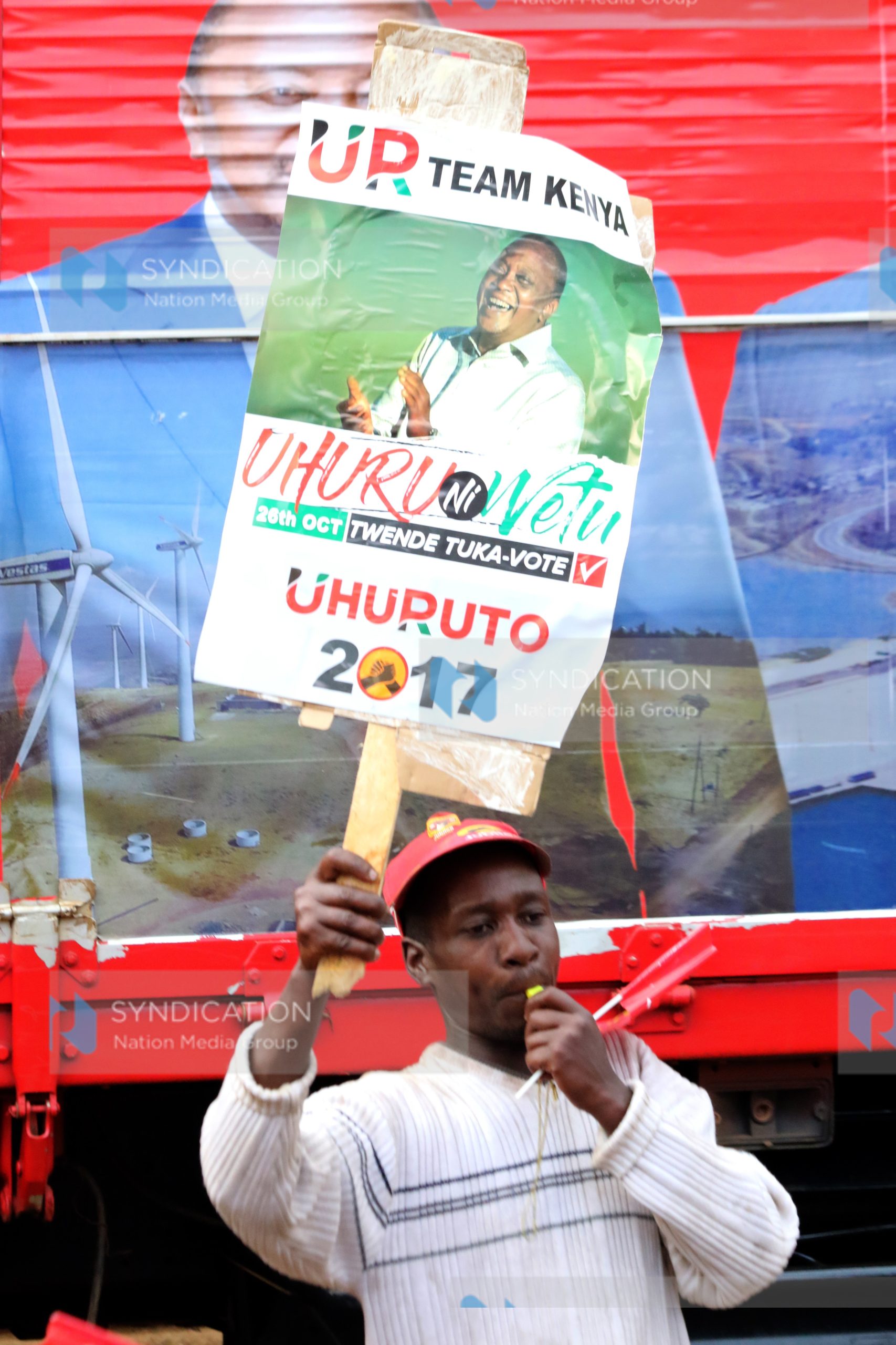 A Jubilee backer lifts placards during a campaign rally
