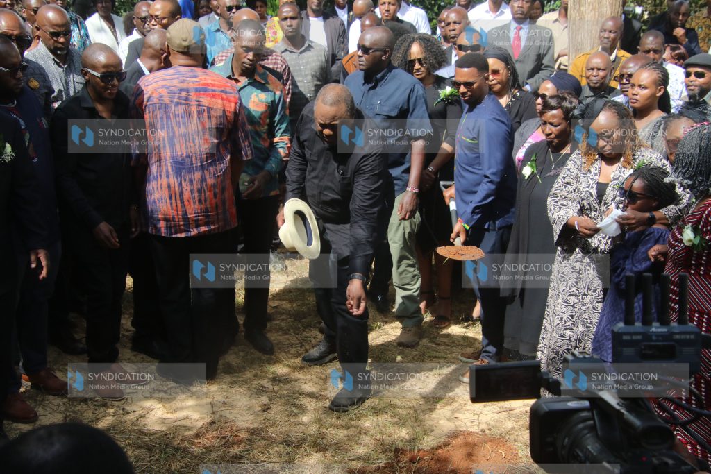 Former President Uhuru Kenyatta tosses soil into the grave of Kanja Waruru