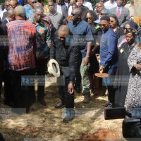 Former President Uhuru Kenyatta tosses soil into the grave of Kanja Waruru