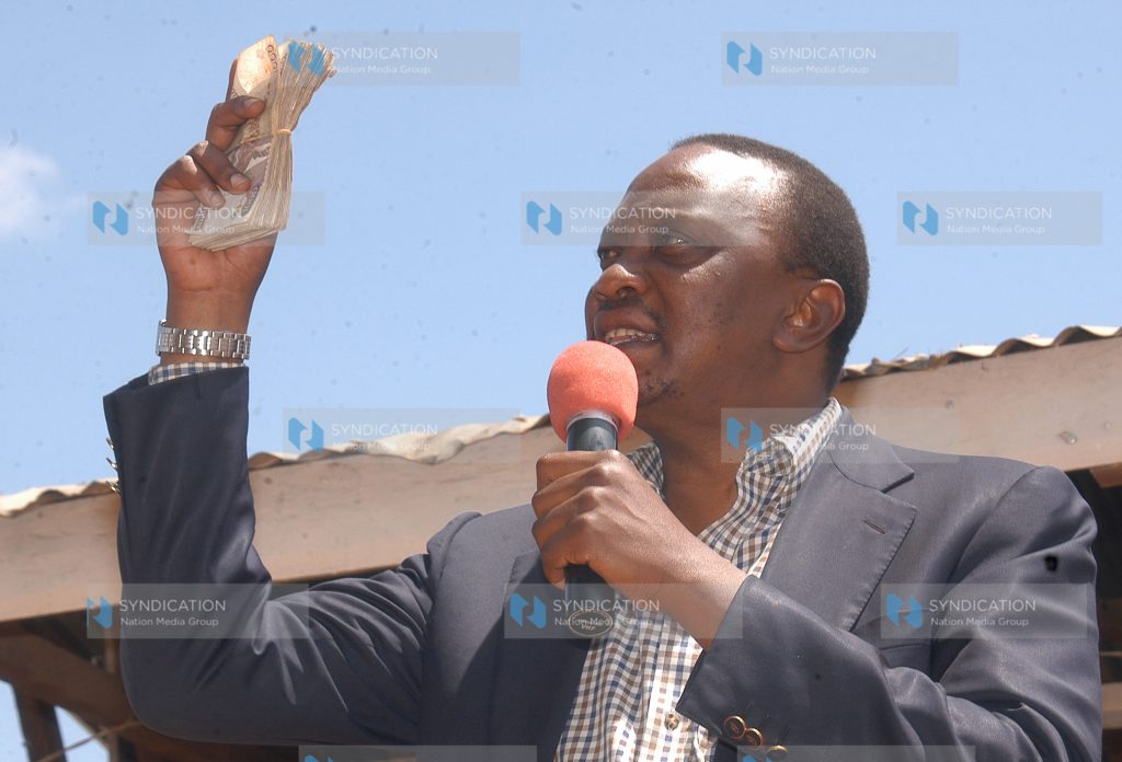 Deputy Prime Minister Uhuru Kenyatta displays notes during a fund drive for Nanyuki PCEA parish