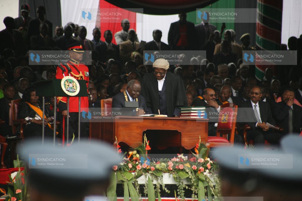 President Mwai Kibaki appends his signature to the new constitution