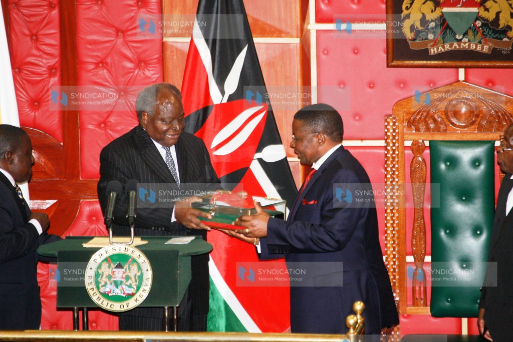 President Mwai Kibaki hands over the original copy of the new constitution