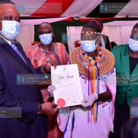 President Uhuru Kenyatta presents a title deed to Michenua Lekurayo from Samburu County