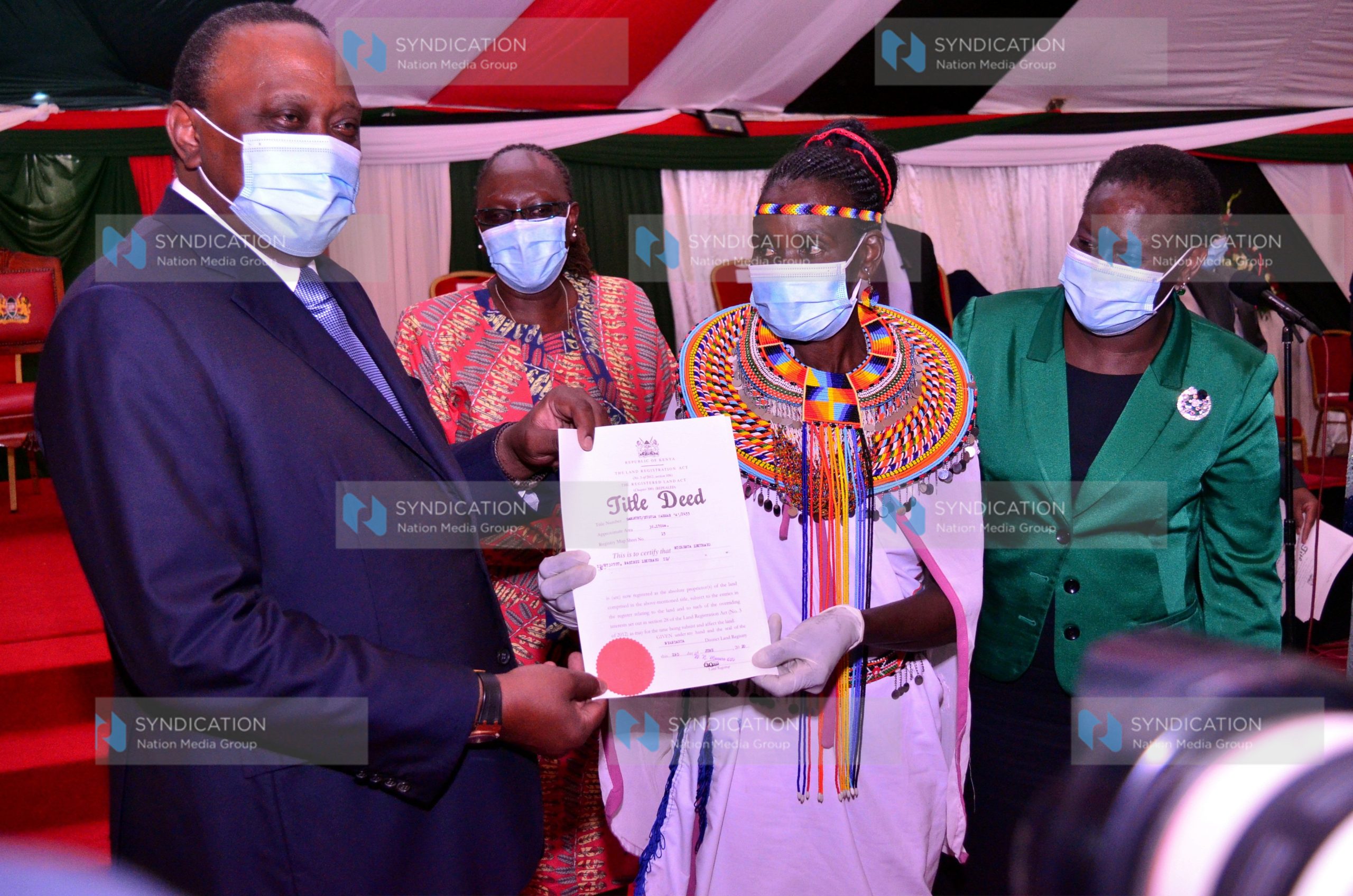 President Uhuru Kenyatta presents a title deed to Michenua Lekurayo from Samburu County
