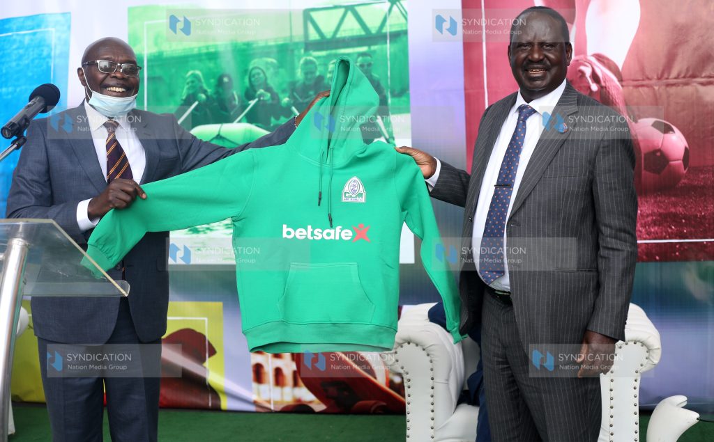Gor Mahia Chairman Ambrose Rachier hands over a Gor Mahia Hood to Gor Mahia patron Raila Odinga