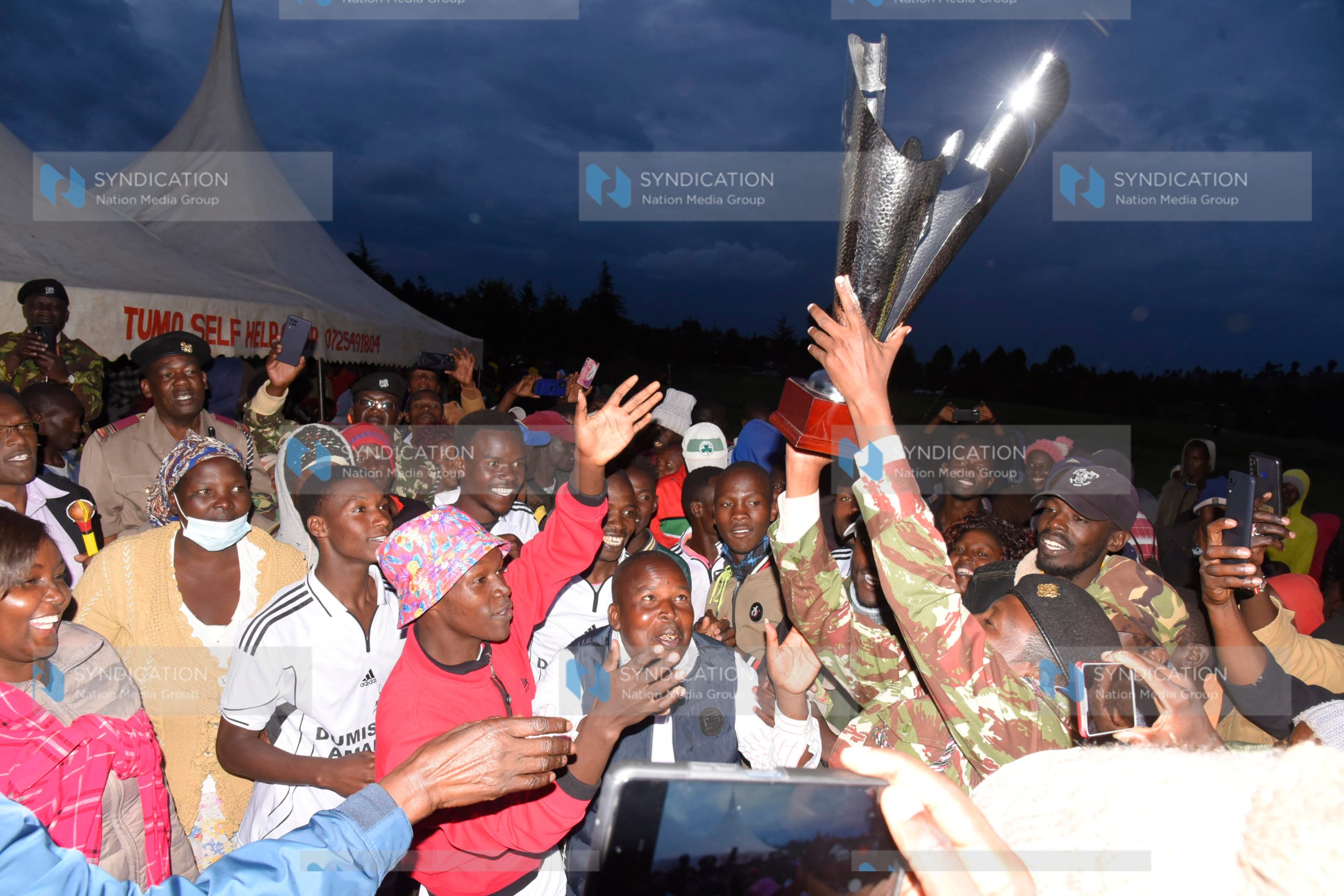 People celebrate winning the trophy after the final match between Boca Junior Football Club and Kaliet FC