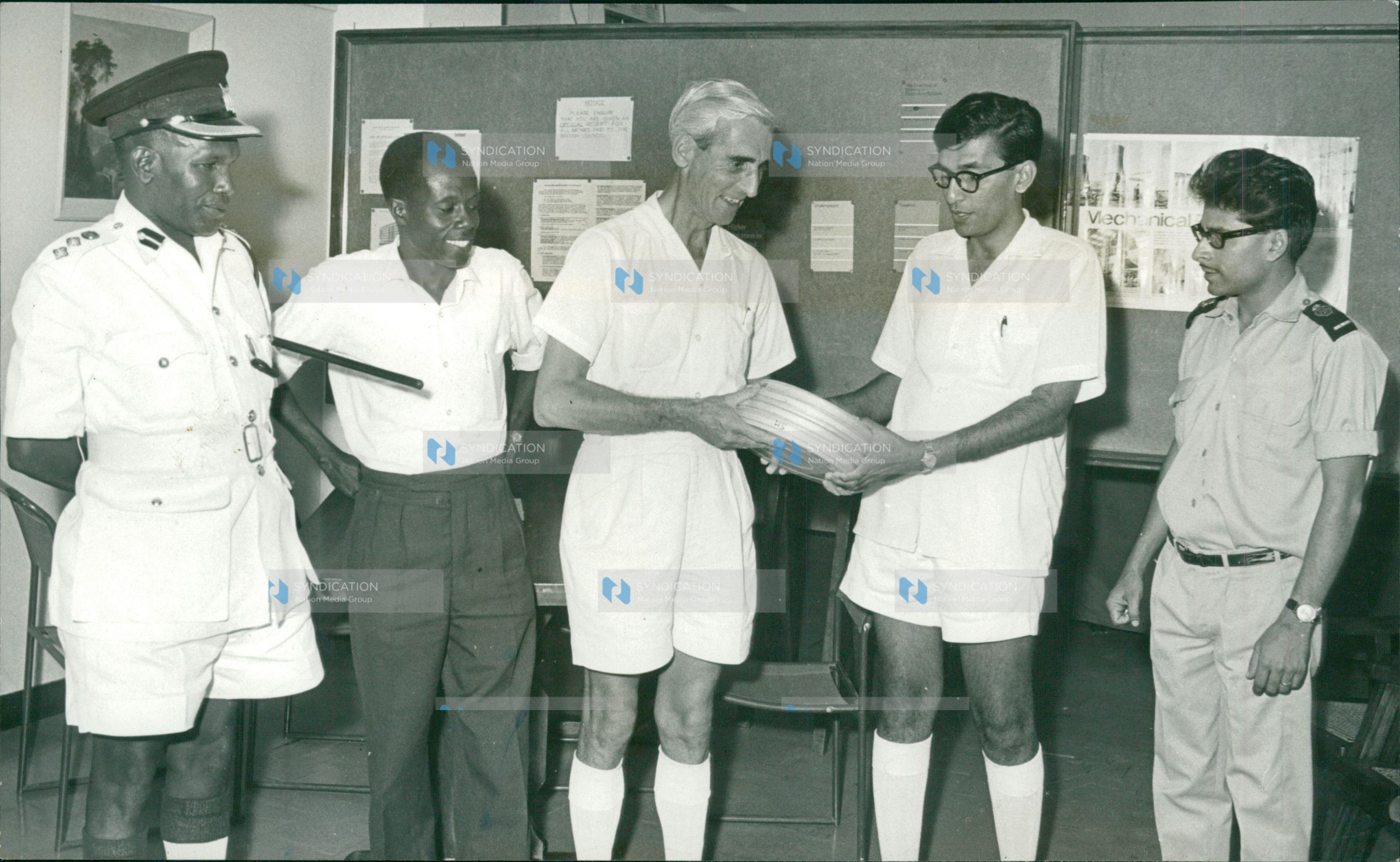 Mr R.F. Harrison (centre), Mombasa director of the British Council, hands over road-safety films