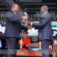 President William Ruto [ R] is handed the instruments of power [sword]