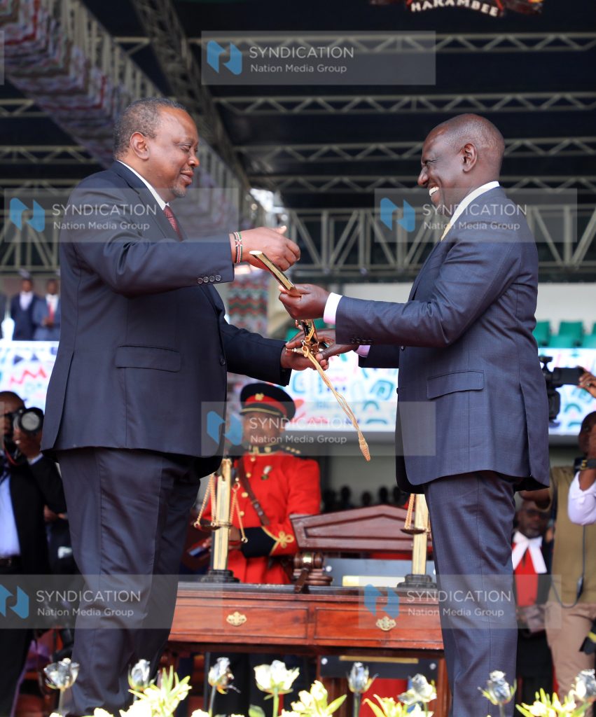 President William Ruto [ R] is handed the instruments of power [sword]