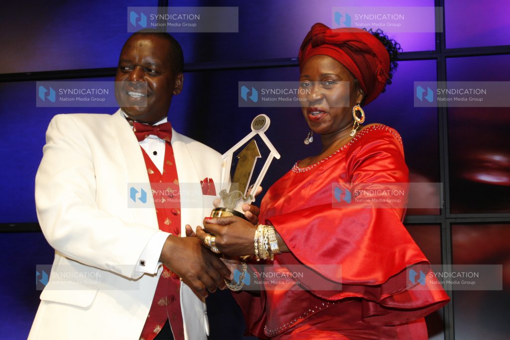 Finance minister Amos Kimunya presents a trophy to Top Image Chief Executive officer Jennifer Barassa
