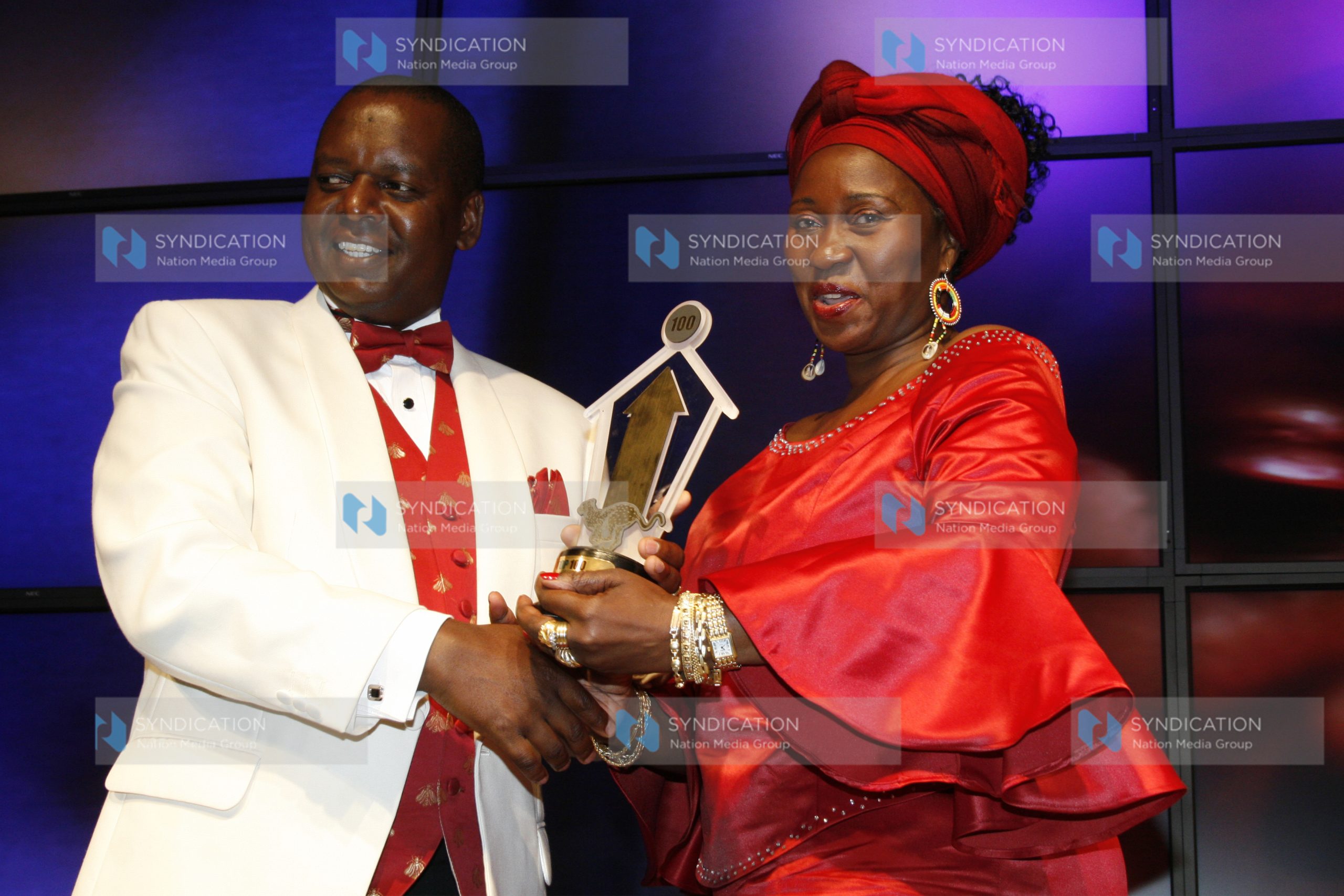 Finance minister Amos Kimunya presents a trophy to Top Image Chief Executive officer Jennifer Barassa