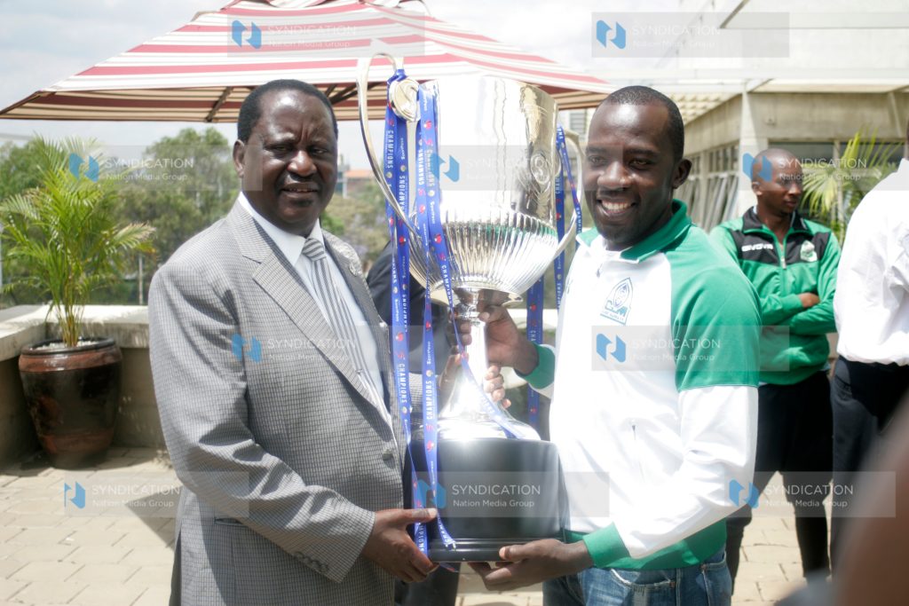 Gor Mahia captain Jerim Onyango hands over the SportPesa Premier League trophy to CORD leader and club patron Raila Odinga