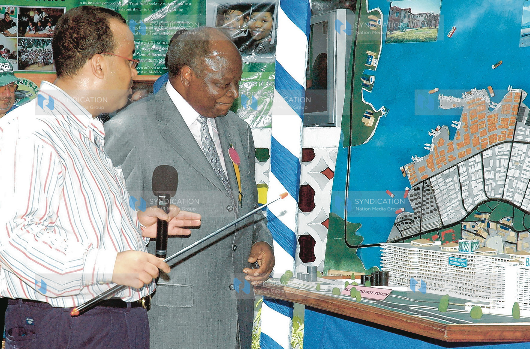 The chief executive officer of the TAL Group Twalib Hatayan shows President Mwai Kibaki the new proposed construction site