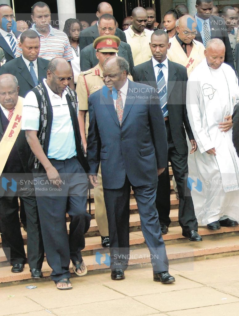 President Mwai Kibaki is escorted out of the Holy Family Basilica by Gatundu North MP Mr. Patrick Muiruri