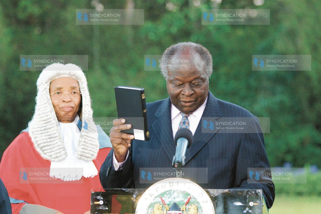 President Mwai Kibaki holds the Bible as he is sworn in at State House
