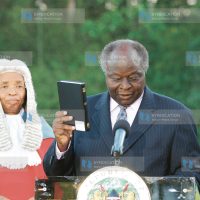 President Mwai Kibaki holds the Bible as he is sworn in at State House