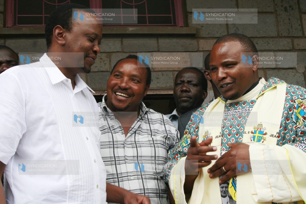 Deputy Prime Minister Uhuru Kenyatta and Embakasi MP aspirant Ferdinand Waititu listen to Fr. Simon Mwangi