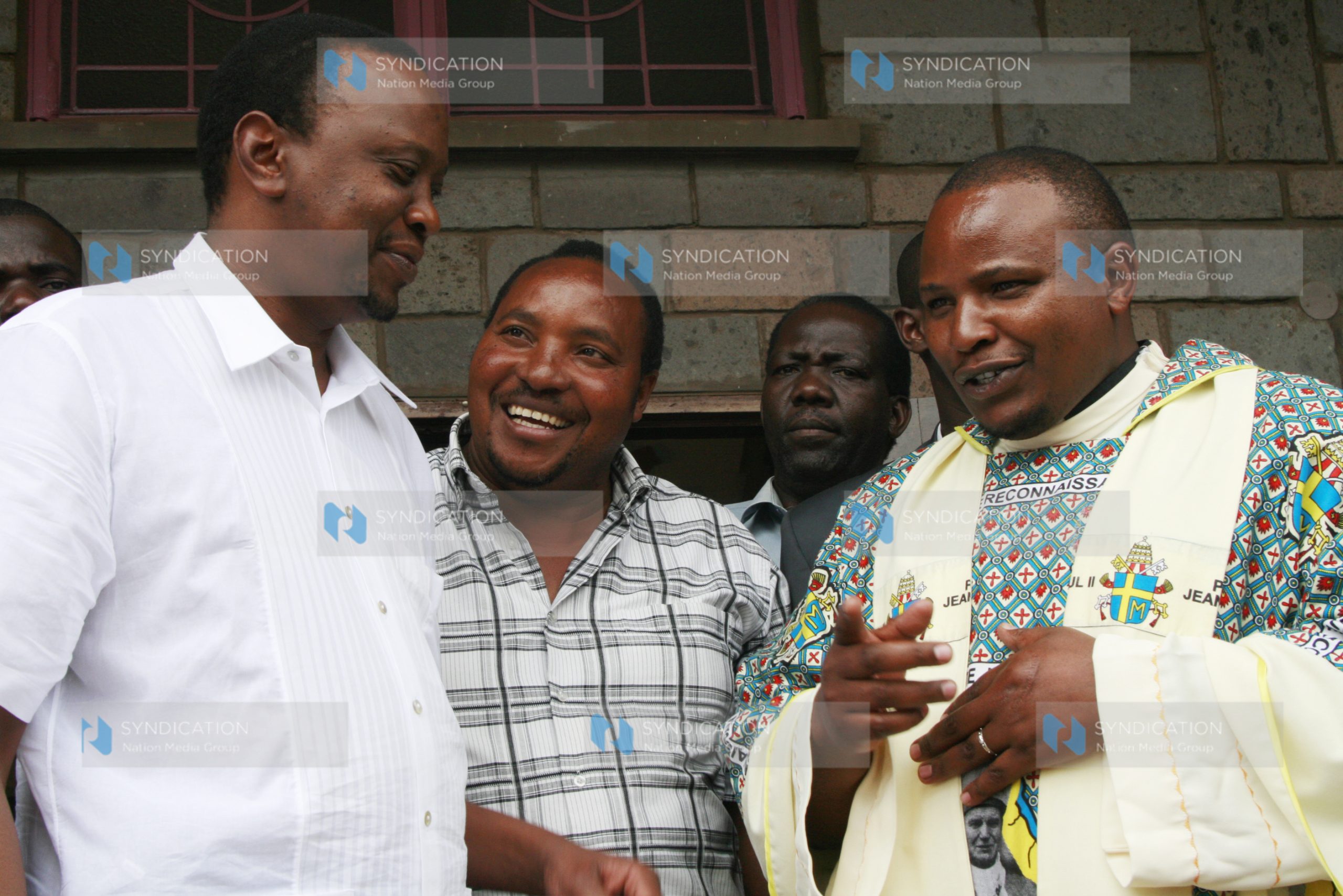Deputy Prime Minister Uhuru Kenyatta and Embakasi MP aspirant Ferdinand Waititu listen to Fr. Simon Mwangi