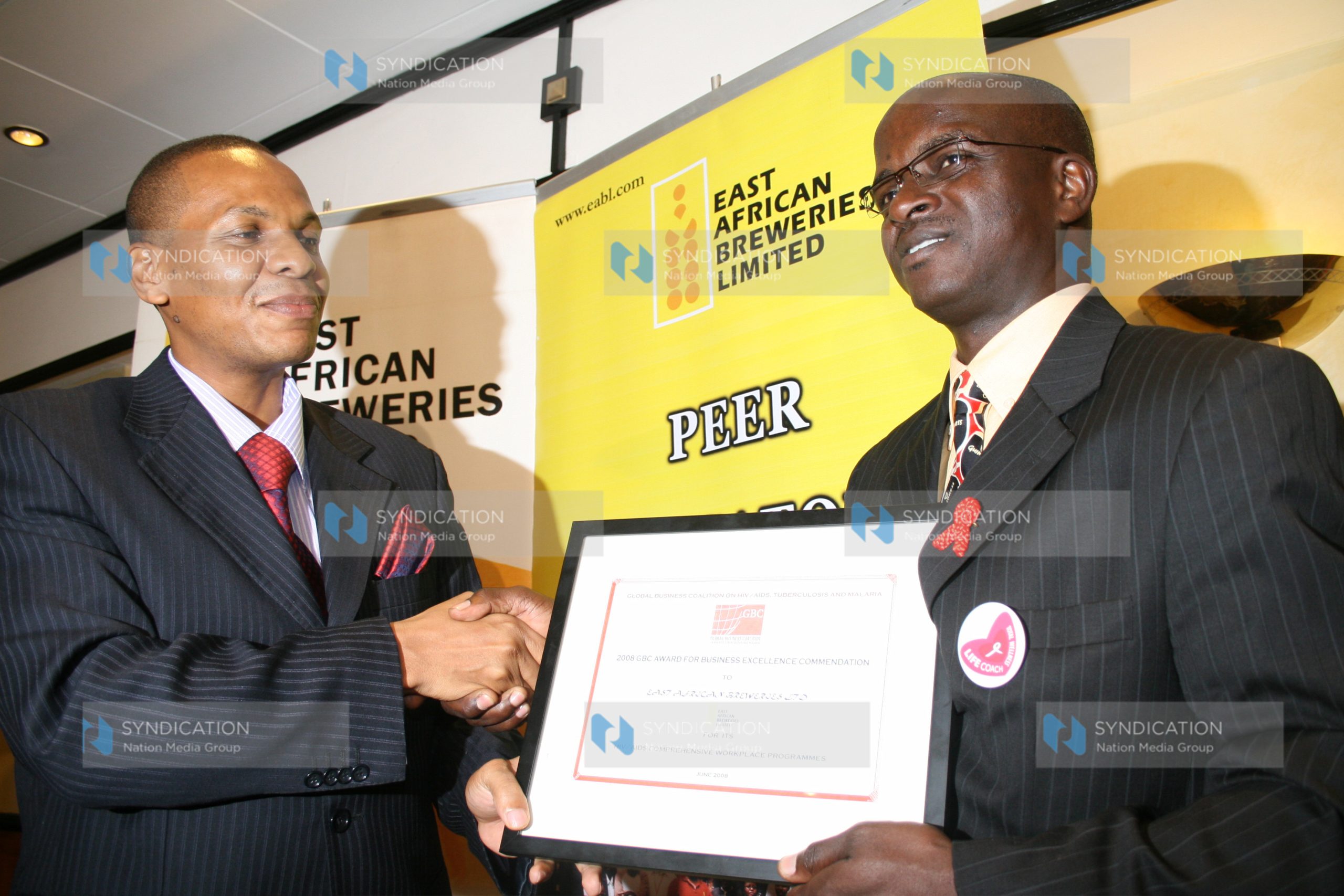 Assistant minister Medical Services Danson Mungatana presents GBC Award that EABL won to Mr. Ben Okumu Chairman EABL Peer Educator Program