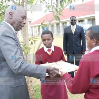 Former President Daniel Arap Moi receives a gift from Form One students Jackline Chepchumba and Brian Ronoh