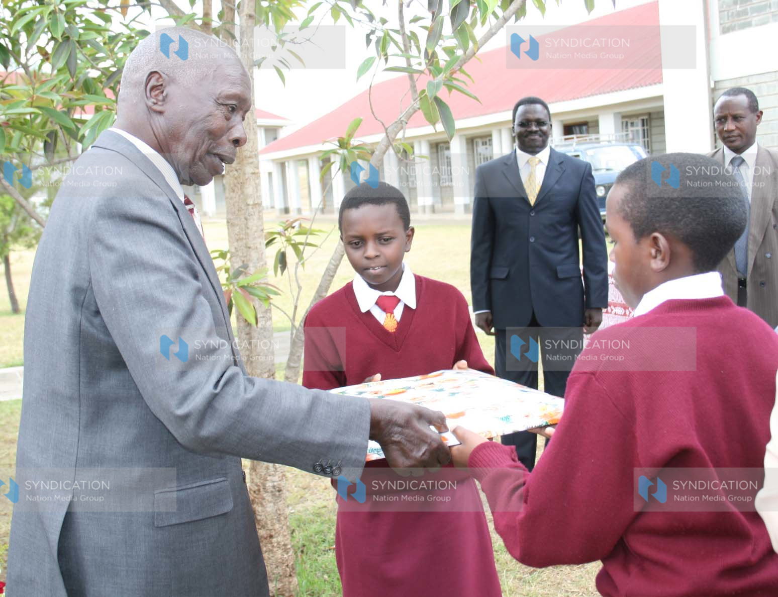 Former President Daniel Arap Moi receives a gift from Form One students Jackline Chepchumba and Brian Ronoh