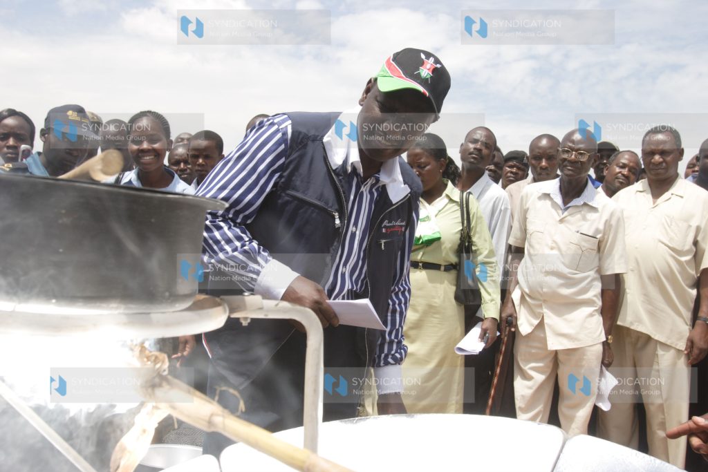 Agriculture Minister William Ruto admires a solar stove