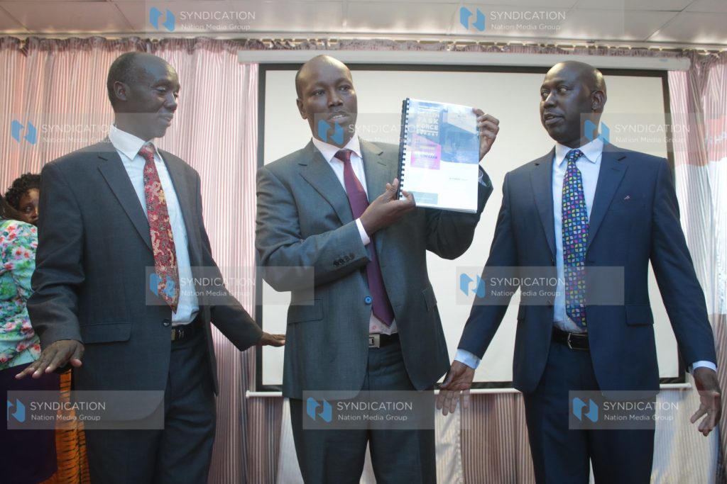 James Tuitoek (left) hands over its findings to Nakuru County Governor Lee Kinyanjui (centre)