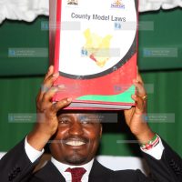 Mwangi Kiunjuri lifts a book containing County Model Laws