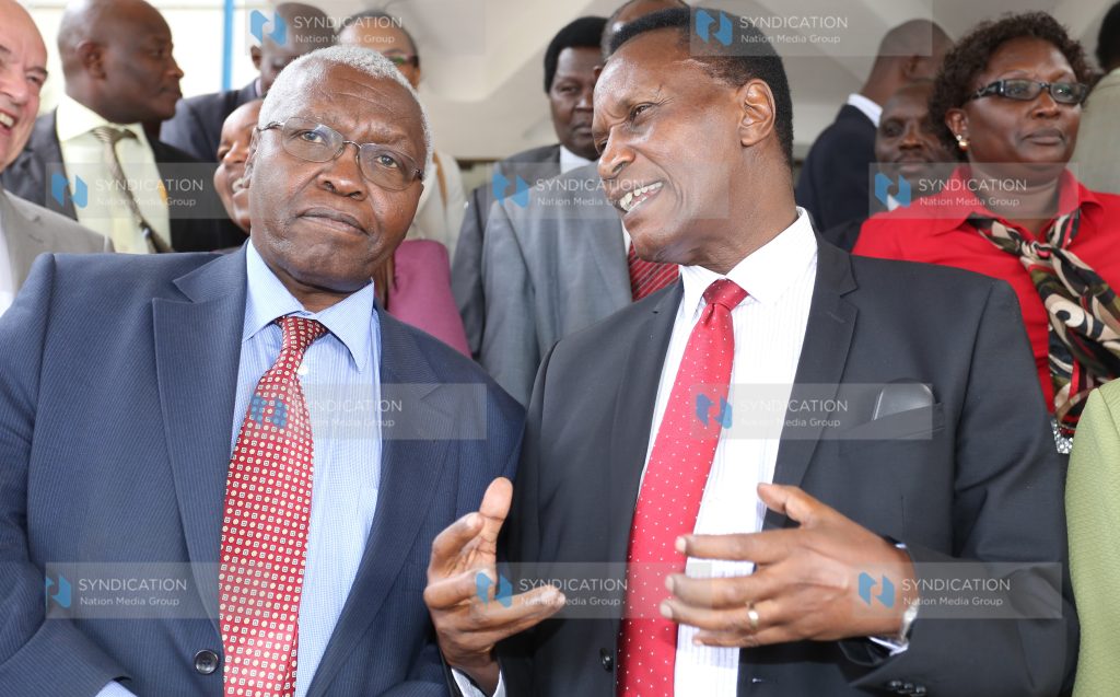 Education Cabinet Secretary Jacob Kaimenyi chatting with CRA commissioner Raphael Munavu